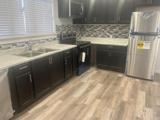 kitchen featuring tasteful backsplash, stainless steel appliances, sink, and light wood-type flooring