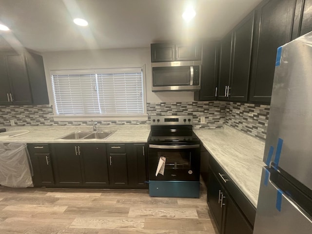 kitchen featuring appliances with stainless steel finishes, sink, backsplash, and light hardwood / wood-style floors