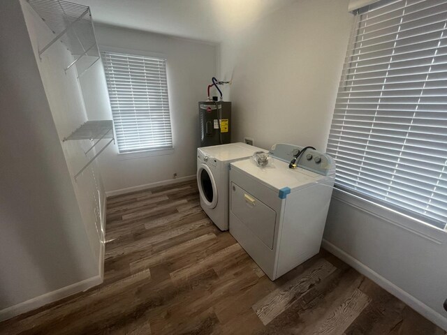 laundry area featuring water heater, dark hardwood / wood-style floors, and washer and clothes dryer