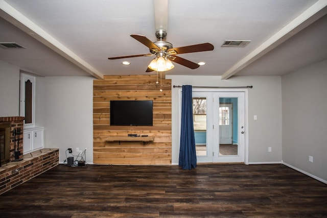 unfurnished living room featuring ceiling fan, a brick fireplace, dark hardwood / wood-style floors, and beam ceiling