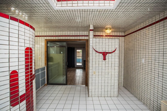 interior space with tile patterned floors and tile walls