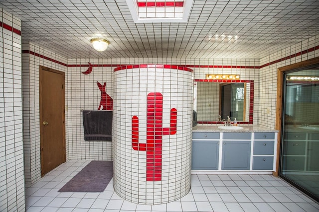 bathroom with tile patterned flooring, vanity, and tile walls