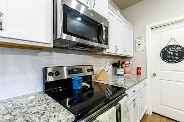 2541 137th St, Lubbock, TX 79423 - kitchen with stainless steel appliances, light stone countertops, white cabinets, and light hardwood / wood-style flooring