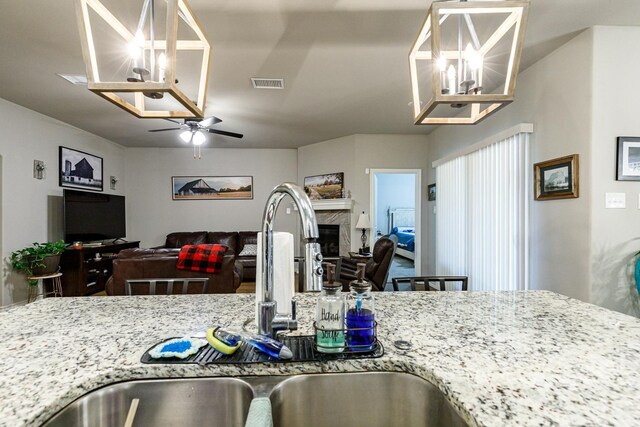 2541 137th St, Lubbock, TX 79423 - kitchen with light stone counters, sink, and ceiling fan with notable chandelier