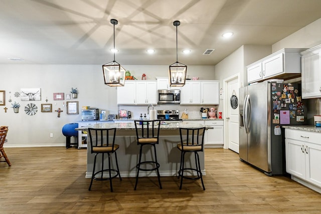 2541 137th St, Lubbock, TX 79423 - kitchen with appliances with stainless steel finishes, a center island, light stone countertops, white cabinets, and decorative light fixtures