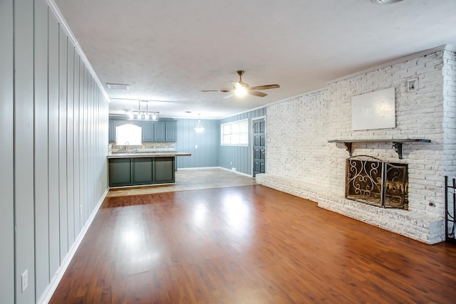 unfurnished living room with ceiling fan, sink, hardwood / wood-style floors, and a brick fireplace