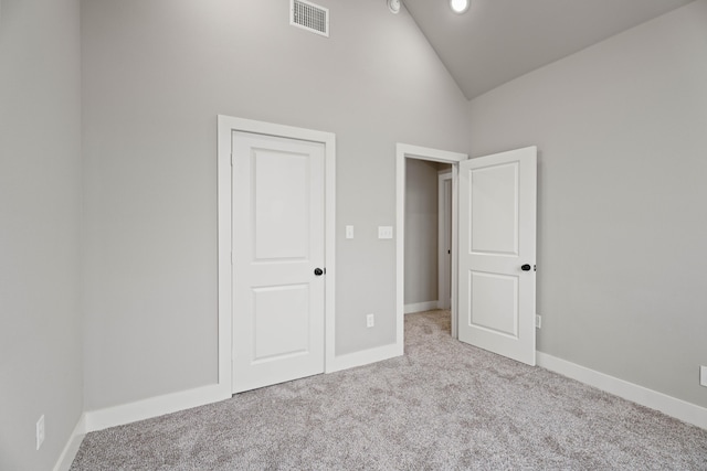 unfurnished bedroom featuring lofted ceiling, baseboards, light carpet, and visible vents