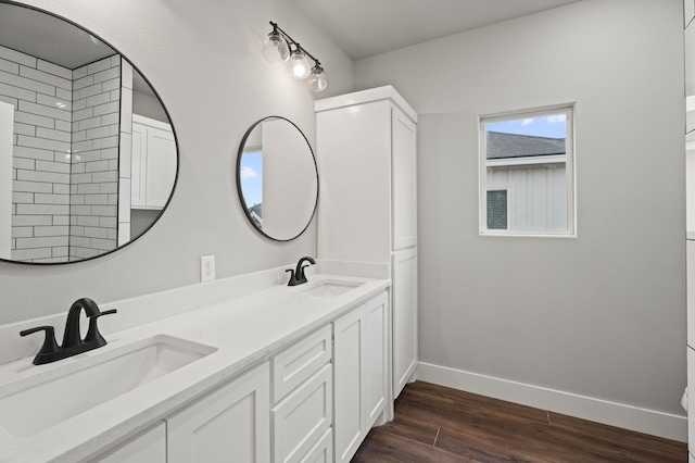 bathroom featuring double vanity, a sink, baseboards, and wood finished floors