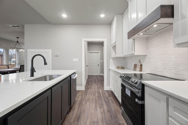 kitchen with a sink, custom range hood, light countertops, and electric stove