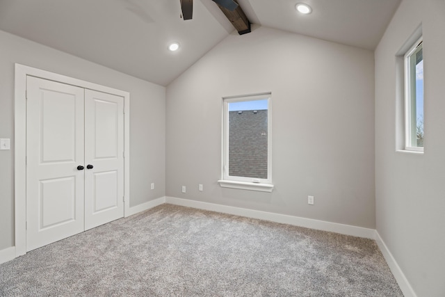 unfurnished bedroom featuring a closet, light carpet, lofted ceiling with beams, and baseboards