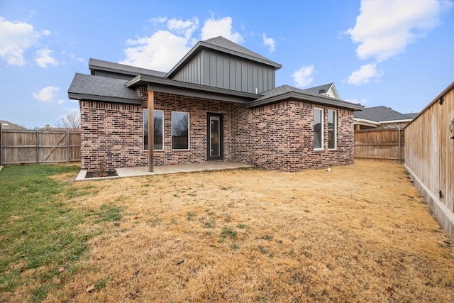 rear view of property featuring a yard, brick siding, a patio area, and a fenced backyard