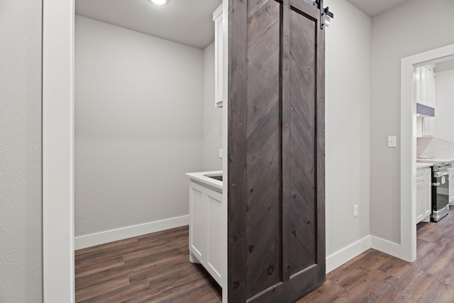 interior space with dark wood-style floors, a barn door, and baseboards