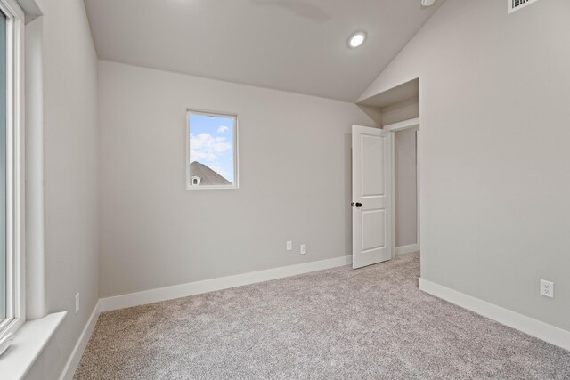 spare room featuring recessed lighting, light carpet, visible vents, baseboards, and vaulted ceiling