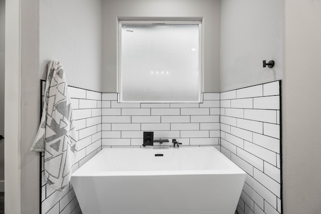 full bath with a sink, a freestanding tub, and tile walls