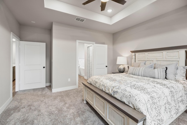 bedroom featuring a tray ceiling, visible vents, light carpet, and baseboards