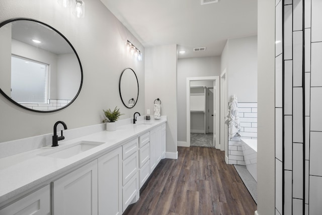 full bathroom featuring wood finished floors, a sink, visible vents, and a walk in closet