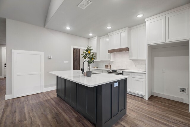 kitchen featuring stainless steel range with electric cooktop, light countertops, an island with sink, and white cabinetry