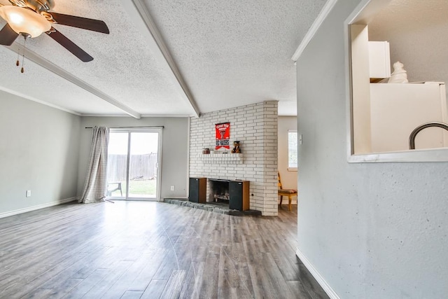 unfurnished living room with hardwood / wood-style flooring, beam ceiling, crown molding, a brick fireplace, and a textured ceiling