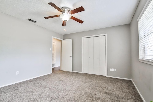 unfurnished bedroom featuring ceiling fan, carpet, a closet, and a textured ceiling