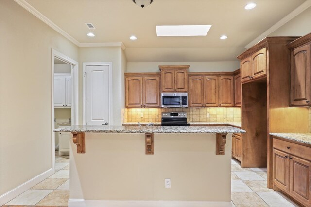 kitchen with light stone countertops, appliances with stainless steel finishes, and a center island with sink