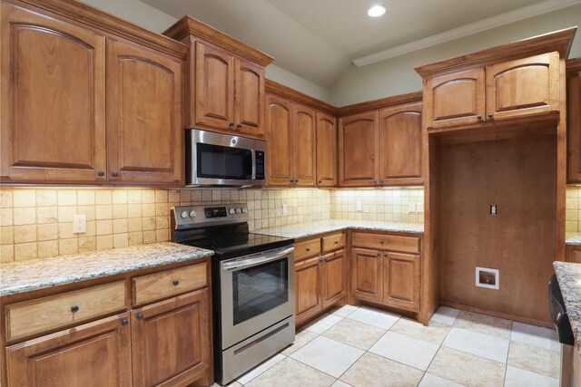 kitchen featuring light tile patterned flooring, tasteful backsplash, crown molding, stainless steel appliances, and light stone countertops