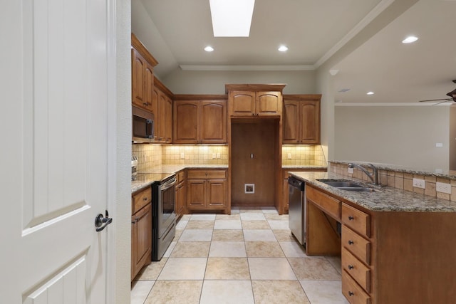 kitchen with sink, backsplash, a skylight, stainless steel appliances, and light stone countertops