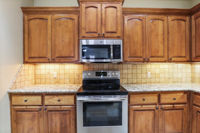 kitchen with decorative backsplash, light stone countertops, and appliances with stainless steel finishes