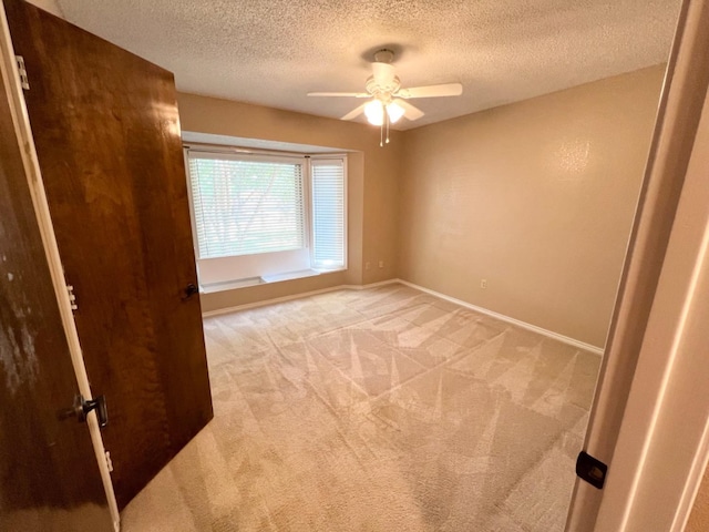 empty room with light carpet, a textured ceiling, and ceiling fan