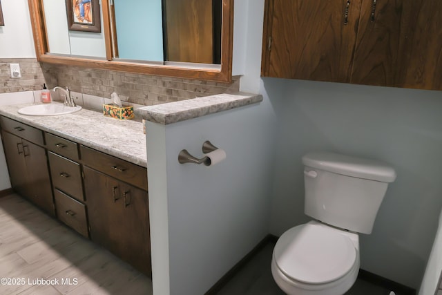 2512 Holliday Dr, Plainview, TX 79072 - bathroom featuring toilet, vanity, decorative backsplash, and baseboards