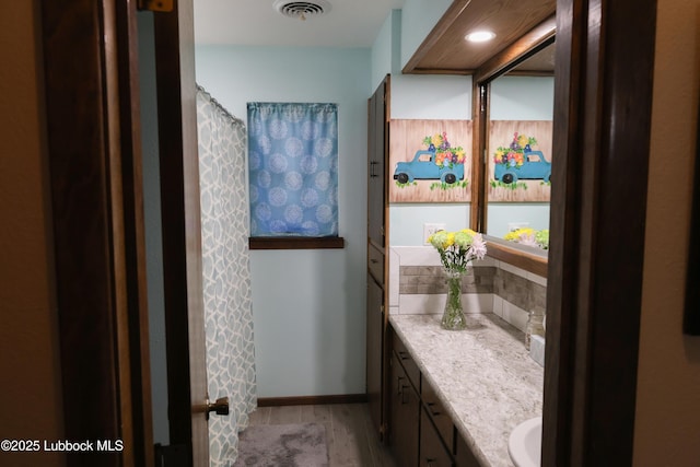 2512 Holliday Dr, Plainview, TX 79072 - bathroom with vanity, wood finished floors, decorative backsplash, and baseboards