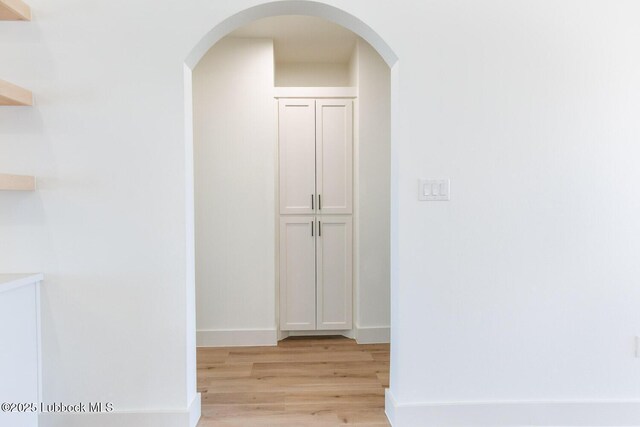 7450 55th St, Lubbock, TX 79407 - hallway with light wood-style flooring, arched walkways, and baseboards