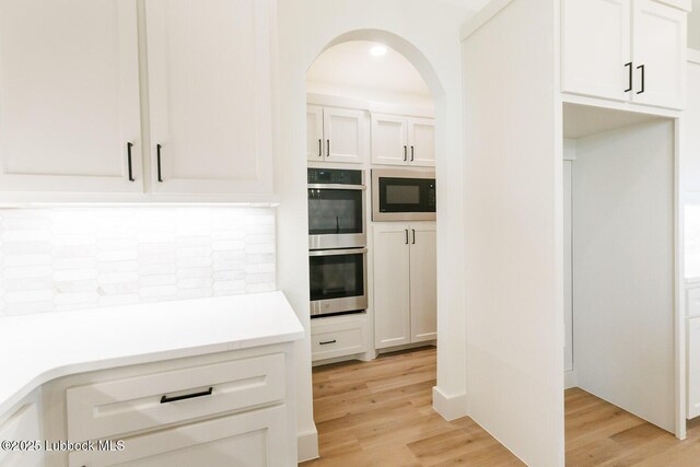 7450 55th St, Lubbock, TX 79407 - kitchen with stainless steel double oven, backsplash, light wood-type flooring, and white cabinets
