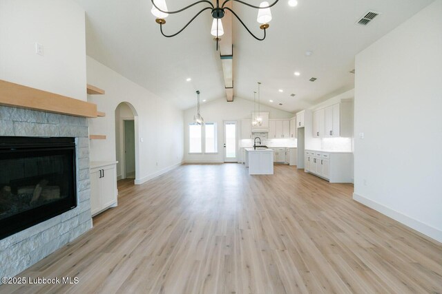 7450 55th St, Lubbock, TX 79407 - unfurnished living room with a sink, a chandelier, a fireplace, light wood-style flooring, and baseboards
