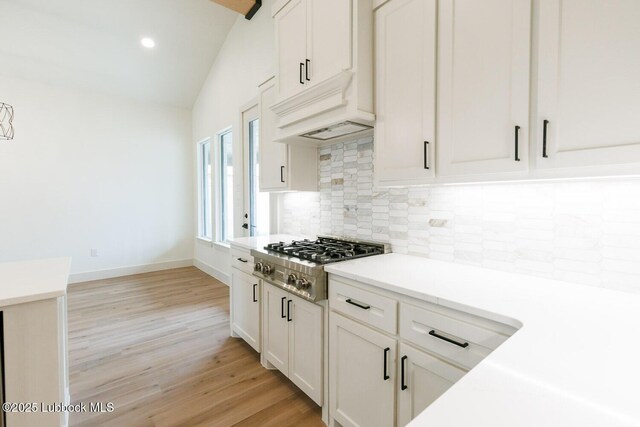 7450 55th St, Lubbock, TX 79407 - kitchen featuring stainless steel gas cooktop, tasteful backsplash, light wood-style flooring, vaulted ceiling, and light countertops
