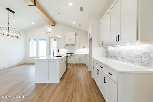7450 55th St, Lubbock, TX 79407 - kitchen featuring a sink, light wood-style flooring, white cabinets, an island with sink, and light countertops