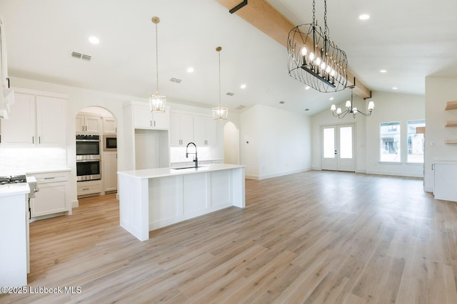 7450 55th St, Lubbock, TX 79407 - kitchen featuring a sink, stainless steel appliances, arched walkways, open floor plan, and a kitchen island with sink