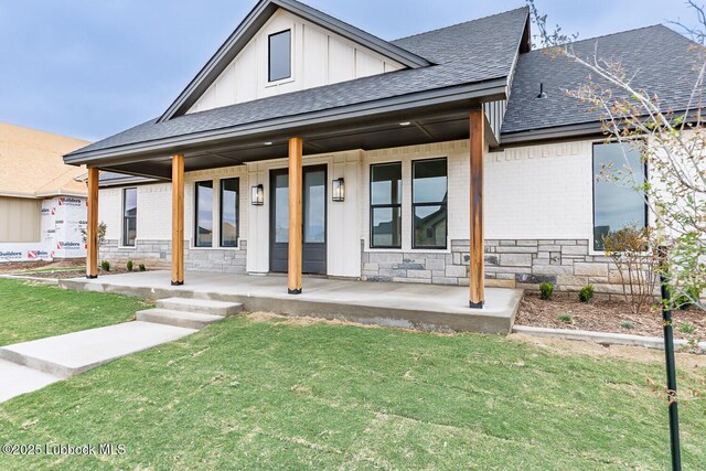 7450 55th St, Lubbock, TX 79407 - view of front of home with a porch, a shingled roof, brick siding, a front lawn, and stone siding