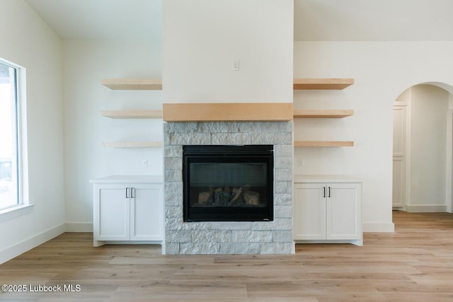 7450 55th St, Lubbock, TX 79407 - detailed view of wood finished floors, a glass covered fireplace, arched walkways, and baseboards