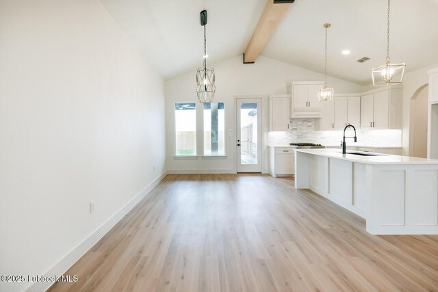 7450 55th St, Lubbock, TX 79407 - kitchen with a sink, a chandelier, decorative backsplash, light wood finished floors, and light countertops