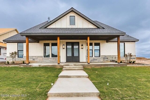 7450 55th St, Lubbock, TX 79407 - view of front of home featuring a shingled roof, covered porch, board and batten siding, brick siding, and a front lawn