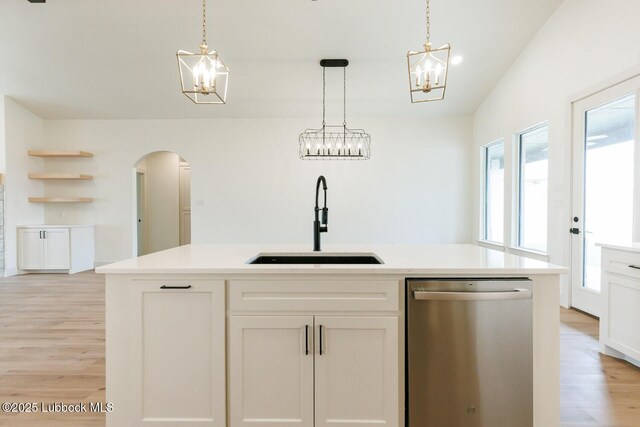 7450 55th St, Lubbock, TX 79407 - kitchen with stainless steel dishwasher, a sink, arched walkways, light wood finished floors, and a chandelier
