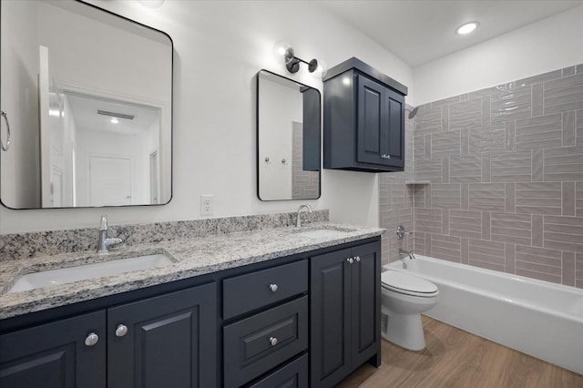 full bathroom featuring vanity, tiled shower / bath combo, wood-type flooring, and toilet