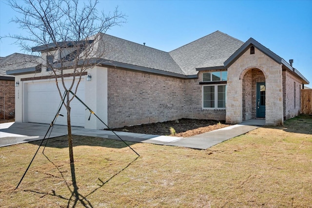 view of front facade with driveway, an attached garage, a shingled roof, a front lawn, and brick siding