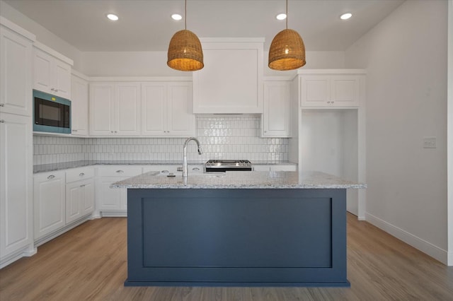 kitchen with built in microwave, decorative light fixtures, and white cabinets