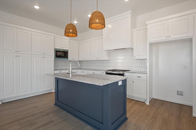 kitchen with built in microwave, hanging light fixtures, white cabinets, light stone countertops, and stove