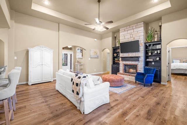 living room with a large fireplace, light hardwood / wood-style floors, and a tray ceiling