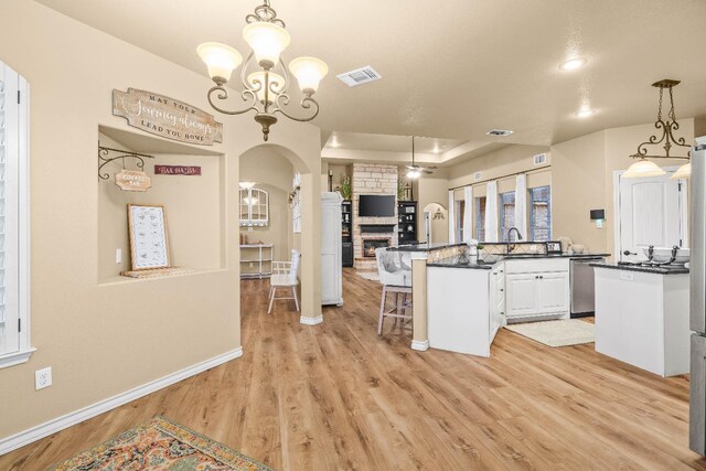 kitchen with stainless steel dishwasher, pendant lighting, a kitchen breakfast bar, and light hardwood / wood-style flooring