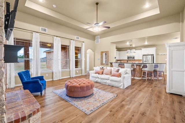 living room featuring ceiling fan, a raised ceiling, and light hardwood / wood-style flooring