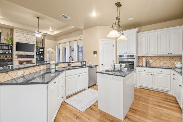 kitchen with appliances with stainless steel finishes, sink, white cabinets, hanging light fixtures, and a center island