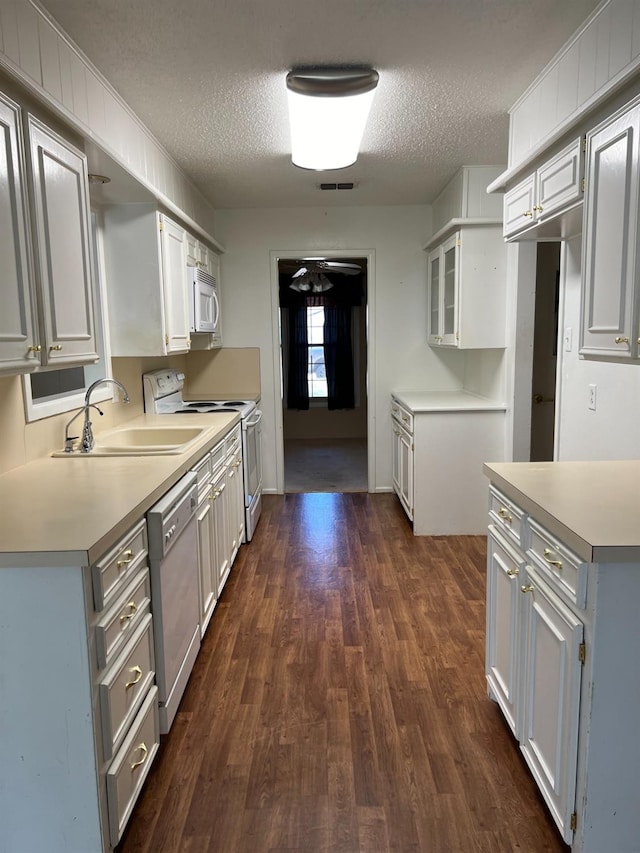 kitchen with sink, white appliances, white cabinetry, dark hardwood / wood-style floors, and a textured ceiling